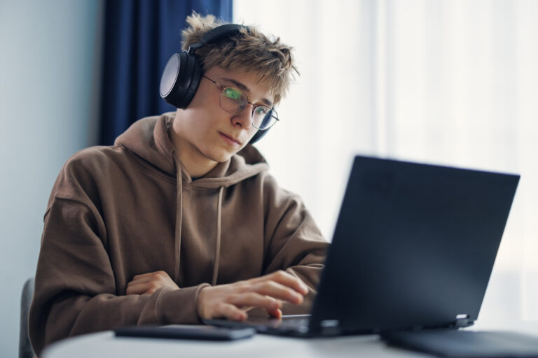 Teenage boy using laptop in a modern city apartment